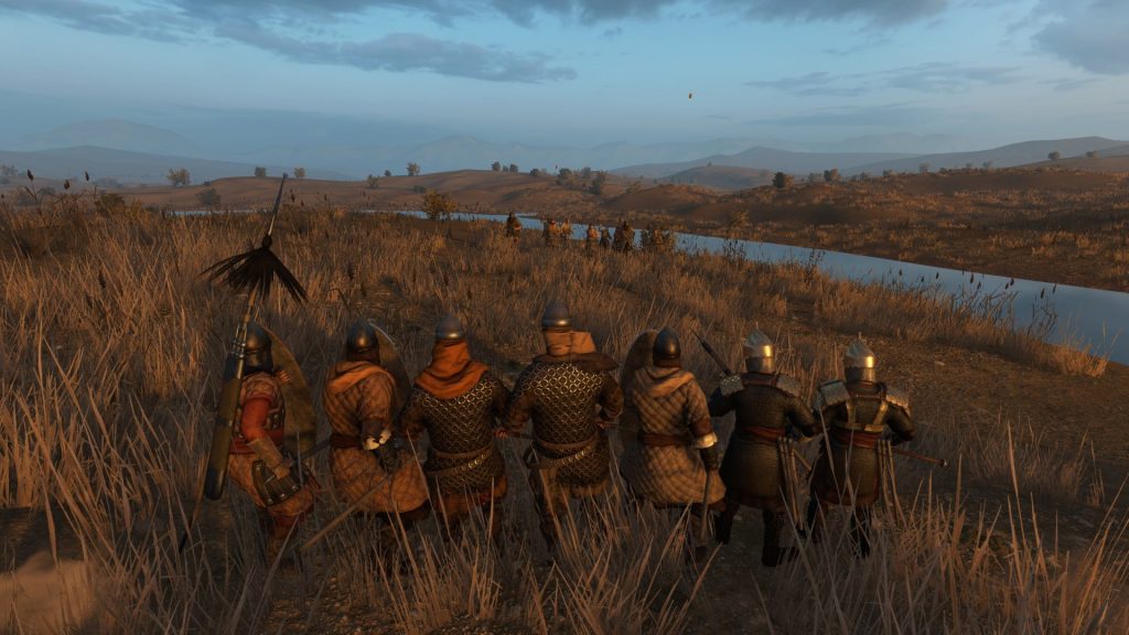 Mount & Blade 2: Bannerlord screenshot showing a small group of soldiers closely together as bandits charge toward them. They're in a tall grass near a river.