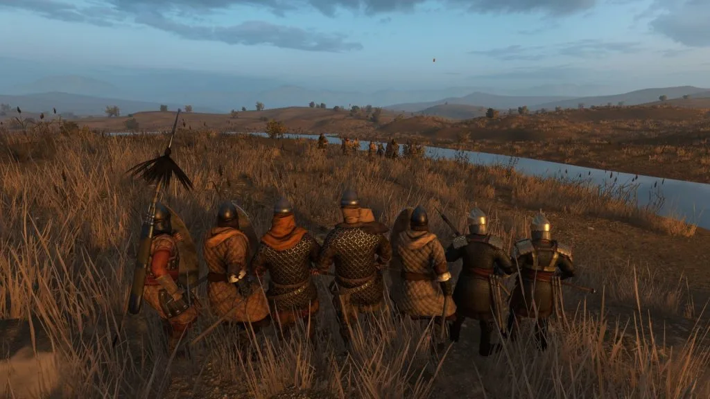 Mount & Blade 2: Bannerlord screenshot showing a small group of soldiers closely together as bandits charge toward them. They're in a tall grass near a river.