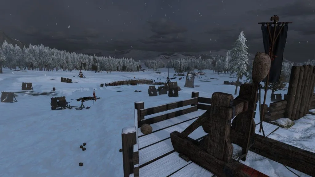 Mount & Blade 2 Bannerlord screenshot of a catapult on a castle wall overlooking a massive army of troops in the distance. The area is covered in snow and a forest of trees in the distance.