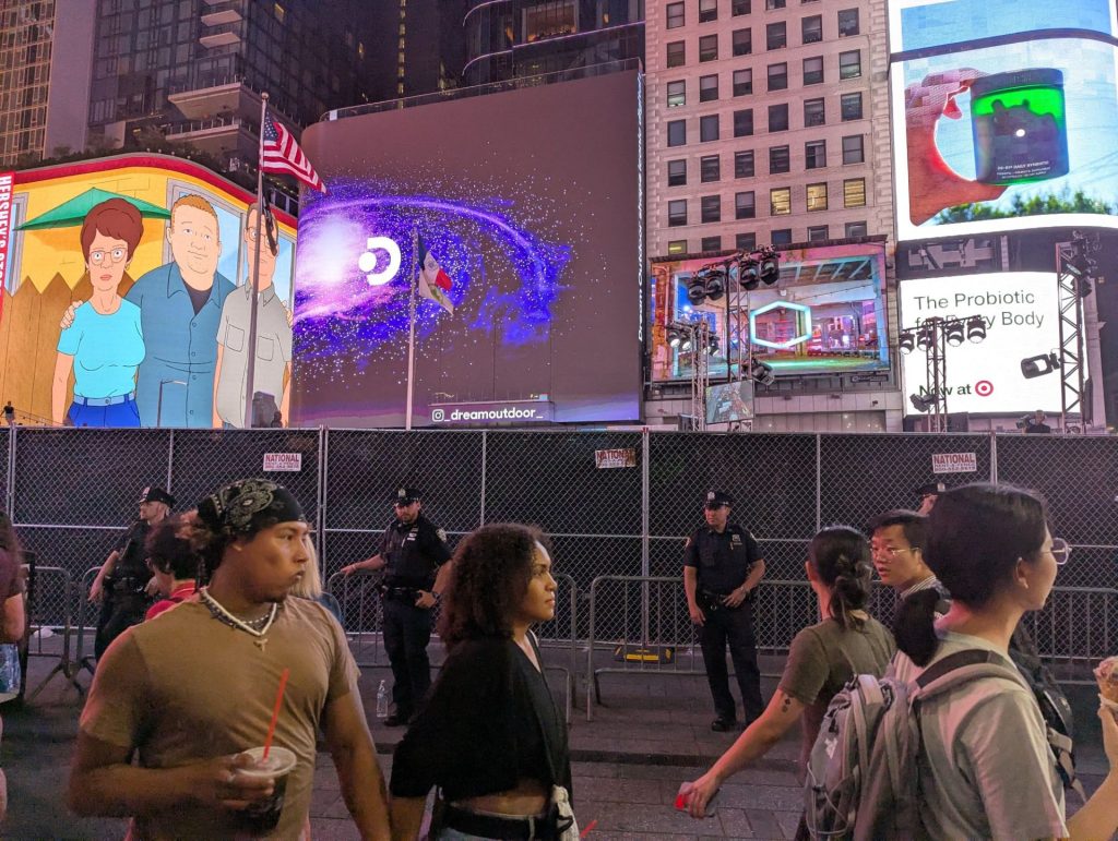 Multiple NYPD Cops in Front of Two Fences in Times Square